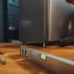 Installation frigo : technicien règle le niveau et la hauteur pour protéger le compresseur